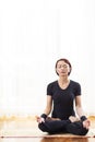 Caucasian Woman Practicing Yoga Indoors. Sitting in Sukhasana Pose Indoors.In Front of Big Sunny Window Royalty Free Stock Photo