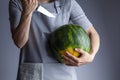 woman is preparing to stab a watermelon using a sharp kitchen knife.