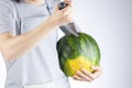 A caucasian woman is preparing to stab a watermelon using a sharp kitchen knife