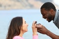 Caucasian woman proposing marriage to man with black skin