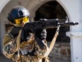 Caucasian woman in a protective suit with a machine gun. A female soldier in a camouflage uniform holds a weapon.