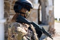 Caucasian woman in a protective suit with a machine gun. A female soldier in a camouflage uniform holds a weapon.