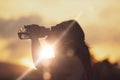 Caucasian woman re-hydrating drinking some water after workout. Outdoor scene with sunset and sun light flare. Empty copy space Royalty Free Stock Photo