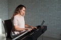 Caucasian woman remotely teaches electric piano playing via video communication on a digital tablet