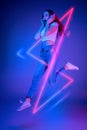 Caucasian woman's portrait isolated on blue studio background in multicolored neon light with geometric luminescent