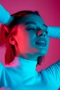 Caucasian woman& x27;s portrait isolated on pink studio background in multicolored neon light Royalty Free Stock Photo