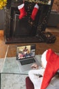 Caucasian woman with santa hat having christmas laptop video call with happy african american family Royalty Free Stock Photo