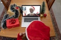 Caucasian woman in santa hat on laptop christmas video call with smiling senior man Royalty Free Stock Photo