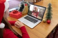 Caucasian woman in santa hat making christmas laptop video call with laughing female friend Royalty Free Stock Photo