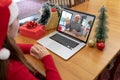 Caucasian woman in santa hat making christmas laptop video call with waving senior father Royalty Free Stock Photo