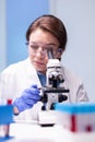 Caucasian woman scientist in white coat looking in high end microscope Royalty Free Stock Photo