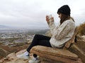 Caucasian woman sitting on a rocky sofa with a winter hat taking a photo to the view from Living Room Trailhead hike