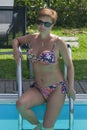 Caucasian woman sitting on stairs of swimming outdoor pool Royalty Free Stock Photo