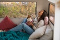 Caucasian woman sitting in a van hugging with dog Jack Russell Terrier. Travel in a camper in the fall.