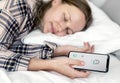 Caucasian woman sleeping in bed with mobile phone in hand Royalty Free Stock Photo