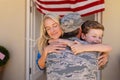 Caucasian woman and son hugging military man on his return home at entrance