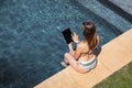 Woman using digital tablet while sitting by the pool Royalty Free Stock Photo