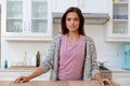 Caucasian woman staning in kitchen looking at camera and smiling