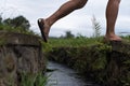 Caucasian woman step over the water ditch. Se has an active vacation in asia and goes for a walk