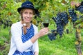 Caucasian woman toasting with glass of wine near bunches of blue