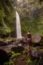 Caucasian woman traveller enjoying waterfall landscape in tropical forest. Energy of water. Travel lifestyle. View from back. Nung