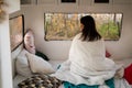 Caucasian woman travels in a motor home. A girl wrapped in a plaid sits in a camper and looks out the window.