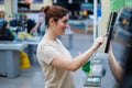 Caucasian woman uses a self-checkout counter. Self-purchase of groceries in the supermarket without a seller Royalty Free Stock Photo