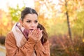 Caucasian woman warming up her hands with her breath during autumn.