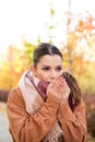 Caucasian woman warming up her hands with her breath during autumn.