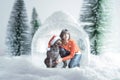 Caucasian woman wearing a christmas pullover and her dog with santa claus hat inside a snow globe. Concept of coronavirus