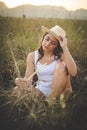 Caucasian woman wearing cowboy hat and sitting on grassland Royalty Free Stock Photo