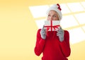 Caucasian woman wearing santa hat holding christmas gift against copy space on yellow background