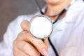 Caucasian woman in white doctor uniform holding a stethoscope in a hand for medical heart examination. Royalty Free Stock Photo