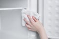 Caucasian woman wipes freezer of the refrigerator with a rag close-up