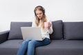 Caucasian woman working home sitting on a sofa with a laptop and a cup of coffee. Stay home, quarantine concept Royalty Free Stock Photo