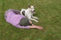 Caucasian woman and  young white mixed breed dog lying next to each other on a cut lawn Royalty Free Stock Photo