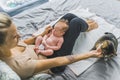 Caucasian woman with blonde hair sitting in bed with newborn baby in her lap petting her pet calico cat. Family animal Royalty Free Stock Photo