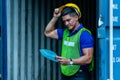 Caucasian worker in safety vest reflective with Safety helmet and ear safety in container depot reading the documents