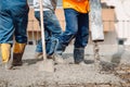 Caucasian workers pouring concrete on slab concrete floor