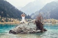 Caucasian yoga man in outdoor meditation sitting on lonely rock island of mountain lake