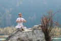 Caucasian yoga man in outdoor meditation sitting on lonely rock island of mountain lake