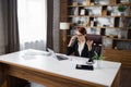 Caucasian young beautiful businesswoman talking on mobile phone while working on laptop Royalty Free Stock Photo