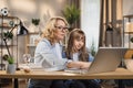 Caucasian young blond woman mother help her beautiful daughter to do homework using laptop Royalty Free Stock Photo