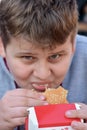 Full face portrait image of young cute boy eating fast food burger