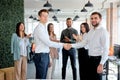 Business men co-workers colleagues greeting each other, shaking hands in modern office