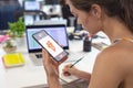 Caucasian young businesswoman writing on diary while using smart phone at desk in office Royalty Free Stock Photo