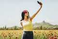 Caucasian young carefree woman hold poppy flower in ears stand in poppy flower field take selfie enjoy springtime. Concept freedom Royalty Free Stock Photo