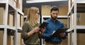 Caucasian young couple of male and female postal workers standing in mail store with carton boxes, talking and Royalty Free Stock Photo