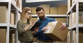 Caucasian young couple of male and female postal workers standing in mail store with carton boxes, talking and