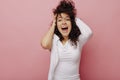 Caucasian young curly brunette woman with open mouth goes crazy holding head on pink background. Royalty Free Stock Photo